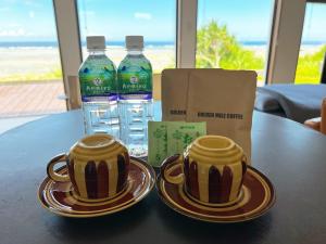 two cups on a table with two bottles of water at ゴールデンマイルヴィラ in Amami