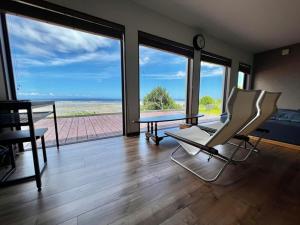 a living room with a table and chairs and a view of the ocean at ゴールデンマイルヴィラ in Amami
