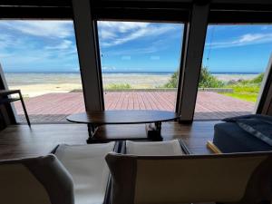 a room with a table and chairs and a view of the ocean at ゴールデンマイルヴィラ in Amami