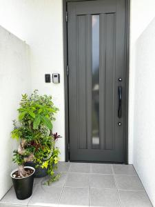 a black door with two potted plants next to it at ゴールデンマイルヴィラ in Amami