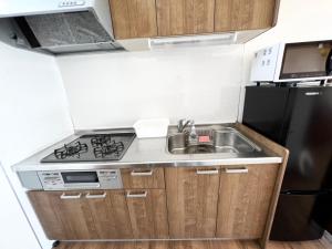 a small kitchen with a sink and a refrigerator at ゴールデンマイルヴィラ in Amami