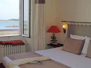 a bedroom with a bed and a large window at Hôtel Aux Tamaris - Vue Mer in Roscoff