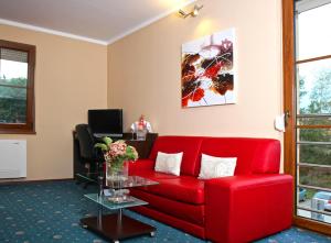 a living room with a red couch and a table at Sportpenzion Pohoda in Pilsen