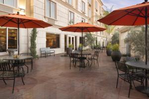 an outdoor patio with tables and chairs and umbrellas at Ayres Hotel Orange in Anaheim