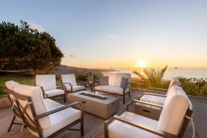 a group of chairs sitting on a patio with the sunset at Vista by AvantStay Stunning Estate w Views of the Pacific Ocean Pool Spa in San Diego