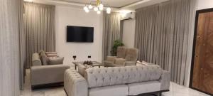 a living room with a couch and chairs and a tv at Vista Lakeside Villas Akosombo in Oko Sombo