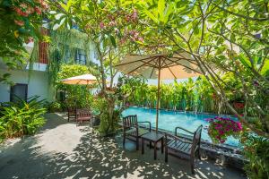 una piscina con bancos y sombrillas en un jardín en Coco Island Villa, en Hoi An