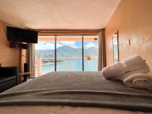 ein Schlafzimmer mit einem großen Bett und einem großen Fenster in der Unterkunft Amigos in San Pedro La Laguna