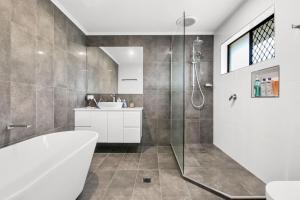 a bathroom with a tub and a sink and a shower at Bell Street 36 Dicky Beach in Caloundra