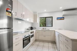 eine weiße Küche mit weißen Schränken und einem Fenster in der Unterkunft Bell Street 36 Dicky Beach in Caloundra