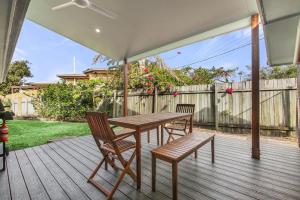 a wooden table and chairs on a deck with an umbrella at Bell Street 36 Dicky Beach in Caloundra