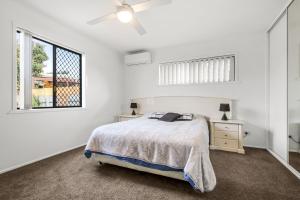 a white bedroom with a bed and a window at Bell Street 36 Dicky Beach in Caloundra