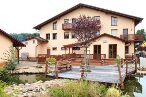 a house with a wooden bridge over a body of water at Sportpenzion Pohoda in Pilsen