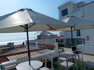 萬查科的住宿－Hospedaje Nuna - Playa Huanchaco，海滩上带桌子和遮阳伞的庭院