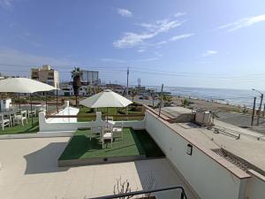 un balcón con mesas y sombrillas y la playa en Hospedaje Nuna - Playa Huanchaco, en Huanchaco