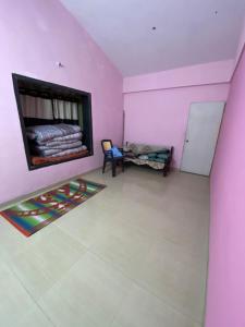 アリバグにあるWoods Prashanti Homestayのベッドと椅子のあるピンク色の部屋