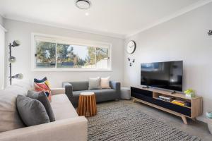 a living room with a couch and a flat screen tv at 'Huxley House' An Elegant Mudgee Retreat with Backyard in Mudgee