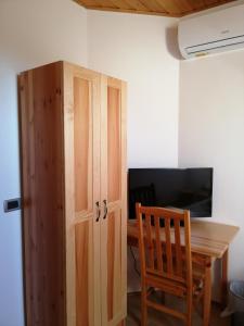 a wooden cabinet next to a desk with a television at Casa Ninfea Panzió in Cserszegtomaj