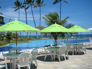 a group of tables and chairs with umbrellas next to a pool at Ancorar Flat Porto de Galinhas-Flat 3311-3314 in Porto De Galinhas