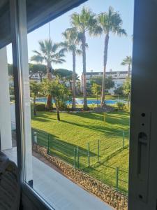 a view from a window of a park with palm trees at Adosado de lujo en El Portil Playa y Golf in El Portil