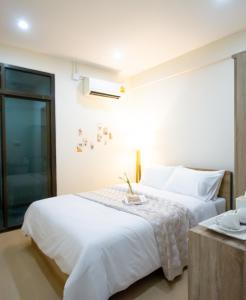 a bedroom with a large white bed and a table at ATC Residence in Bang Su