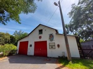 een klein wit gebouw met een rode garage bij Ferienhaus -Alte Feuerwehr- Mittelndorf in Mittelndorf