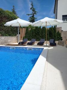 a swimming pool with two umbrellas and two lounge chairs and a swimming pool at Villa M.COCO in Pula
