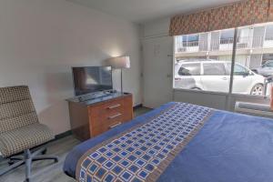 een slaapkamer met een bed, een stoel en een televisie bij White Marlin Inn - Virginia Beach in Virginia Beach