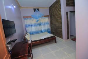 a bedroom with a bed and a desk and a television at Kenthill Guest House in Jinja