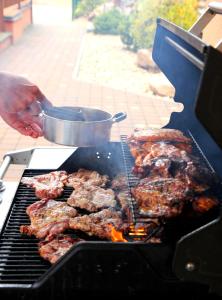 a person is cooking meat on a grill at Sportpenzion Pohoda in Pilsen