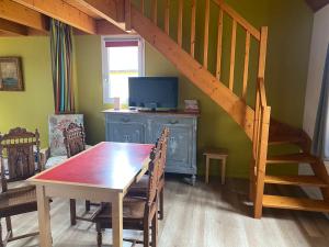 a dining room with a wooden table and a staircase at Cottage Anadwen au pied du lac au duc et son golf in Ploërmel