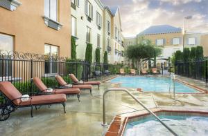 een zwembad met ligstoelen naast een gebouw bij Ayres Hotel Seal Beach in Seal Beach