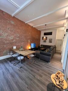 una sala de estar con una pared de ladrillo y una mesa en Luxus Citywohnung in Hannover, en Hannover