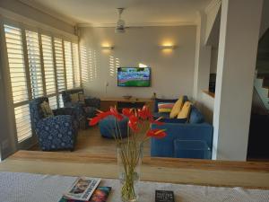 Modern & Luxurious Beachfront Villa في باليتو: غرفة معيشة مع أريكة زرقاء و مزهرية مع الزهور