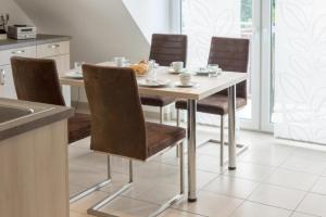 uma cozinha com uma mesa com cadeiras e um estofados de esteira em Fewo-Strandlilie em Norddeich