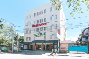 un edificio blanco con un letrero rojo. en RedDoorz Plus at Eco Green Boutique Hotel, en Davao City