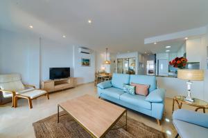 uma sala de estar com um sofá azul e uma mesa em Holidays2Fuengirola Duplex with stunning sea view, terraces,1st line beside port em Fuengirola