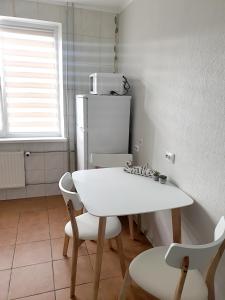 uma cozinha com uma mesa e cadeiras brancas e um frigorífico em Mazeikiai Apartment em Mažeikiai