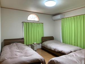 Habitación con 2 camas y cortinas verdes en Yado wa Good Rich Aizumi - Vacation STAY 30409v, 