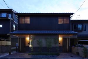 une maison noire avec des lumières à l'avant dans l'établissement 京 吉乃家, à Giommachi