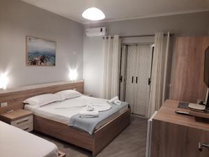 Dormitorio con cama, escritorio y TV en Augustus Hotel, en Dhërmi