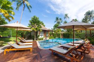 una terraza con sillas y sombrillas junto a una piscina en CHUZ Villas Samui SHA Plus, en Lamai