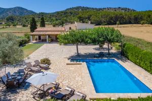 a villa with a swimming pool with chairs and an umbrella at Can Pedro in Pollença