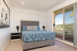 een slaapkamer met een bed en een groot raam bij Coral Sands 3 Pebbly Beach in Forster