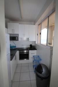 a small kitchen with white cabinets and a black trash can at Cozumel 206 in Umdloti