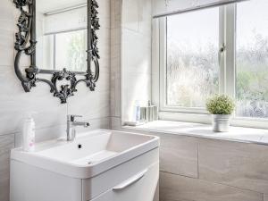 ein weißes Badezimmer mit Waschbecken und Fenster in der Unterkunft Granary Cottage in Pembroke + 28 Fotos