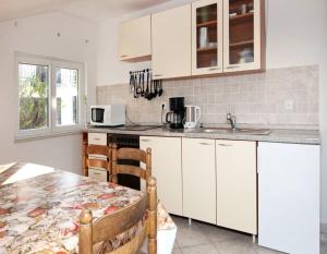 cocina con armarios blancos y mesa en Apartment Aida, en Trogir
