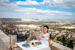 a woman sitting at a table talking on a cell phone at Hydros Cave Suit in Uchisar