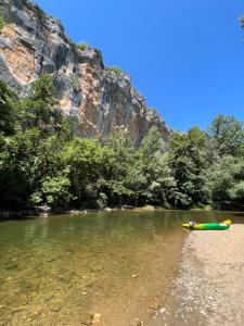 a kayak on the shore of a river next to a mountain at Demeure du Mas de Bessac in Brengues