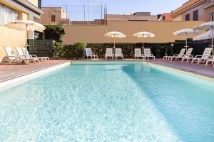 una grande piscina con sedie e ombrelloni di Hotel Villa Margherita a Ladispoli